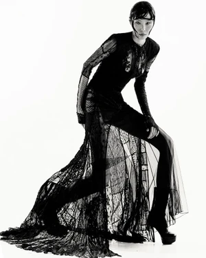 Model Suj Lee in a black lace gown and platform boots against a white studio background for Coeval Magazine