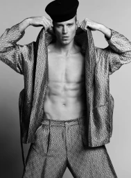 Monochrome portrait of actor Matthew Noszka wearing a patterned robe and black beret against a seamless grey backdrop.