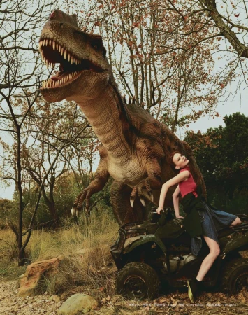 A fashion image featuring a woman posing on an all-terrain vehicle with a large dinosaur model in a wooded, outdoor environment.