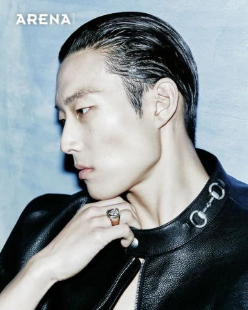Close-up profile of an Asian man with slicked-back hair and black leather jacket against a blue background; fashion portrait.