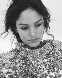 Close-up portrait of model Tahlia Dunn in a heavily embellished sequined garment against a plain background