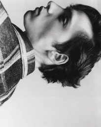 Monochrome close-up profile portrait of a person wearing a plaid shirt against a light background