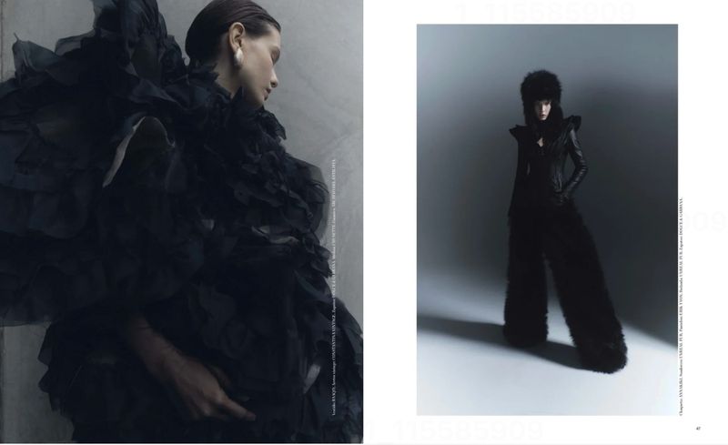 Editorial fashion image with two contrasting female models in elaborate black outfits against a gray studio backdrop in a magazine spread.