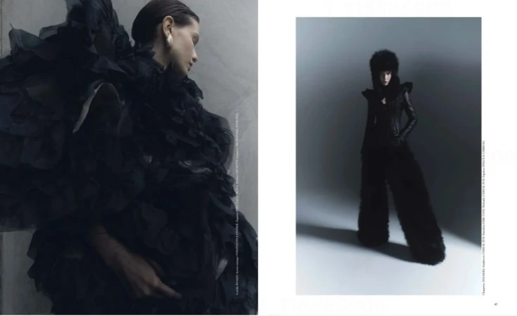 Editorial fashion image with two contrasting female models in elaborate black outfits against a gray studio backdrop in a magazine spread.