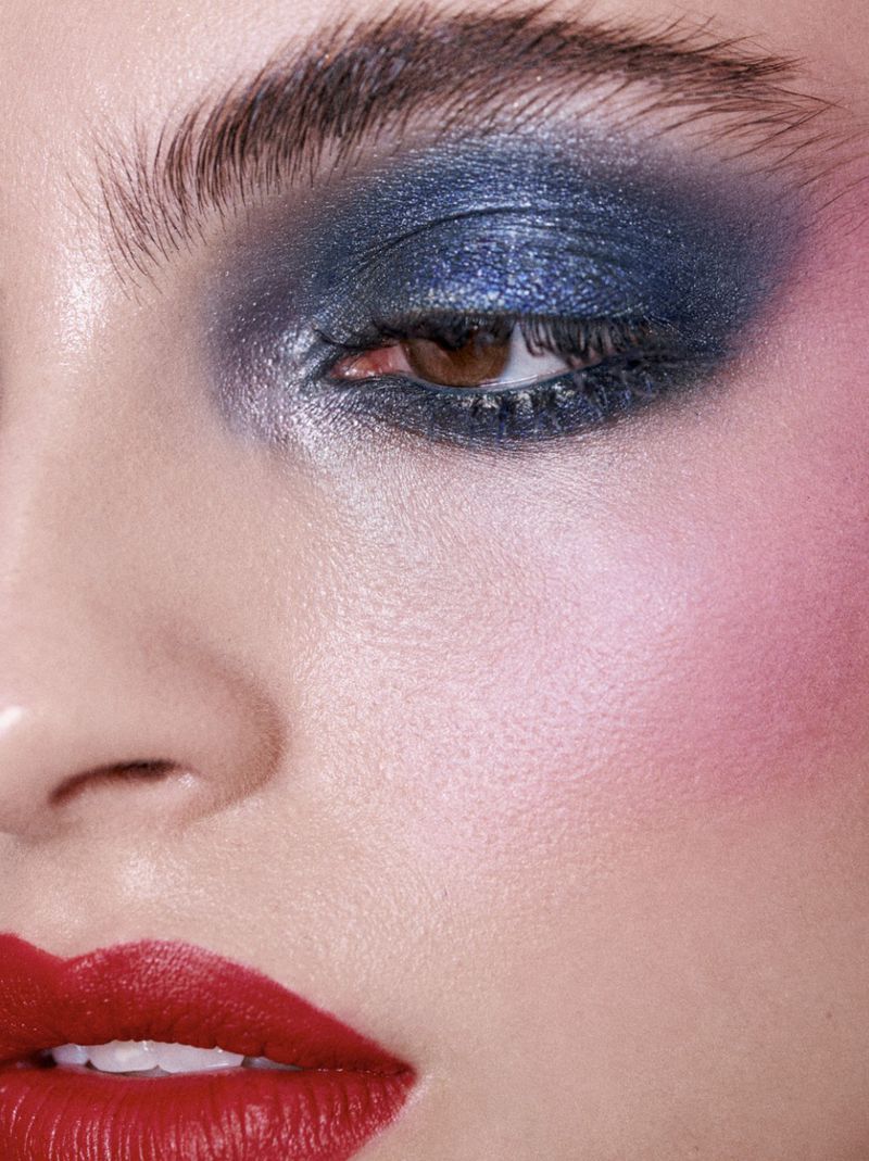 Close-up portrait of a woman with dramatic blue eye shadow and red lipstick, showcasing makeup artistry and beauty techniques.