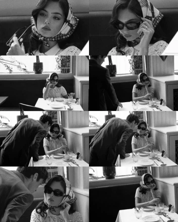 Monochrome shot in a retro restaurant setting shows a woman in a scarf and sunglasses, being approached by a man in a suit.