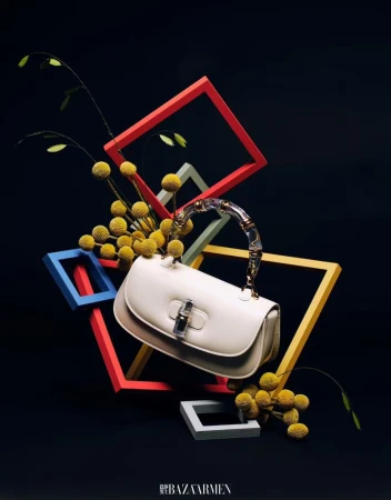 Elegant ivory-colored handbag with clear handle, accented by yellow flowers and geometric shapes against a dark backdrop. Fashion.