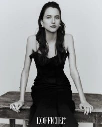 Model Belu Porto in a black dress seated on a wooden table for L'Officiel Thailand project Multiple Identities