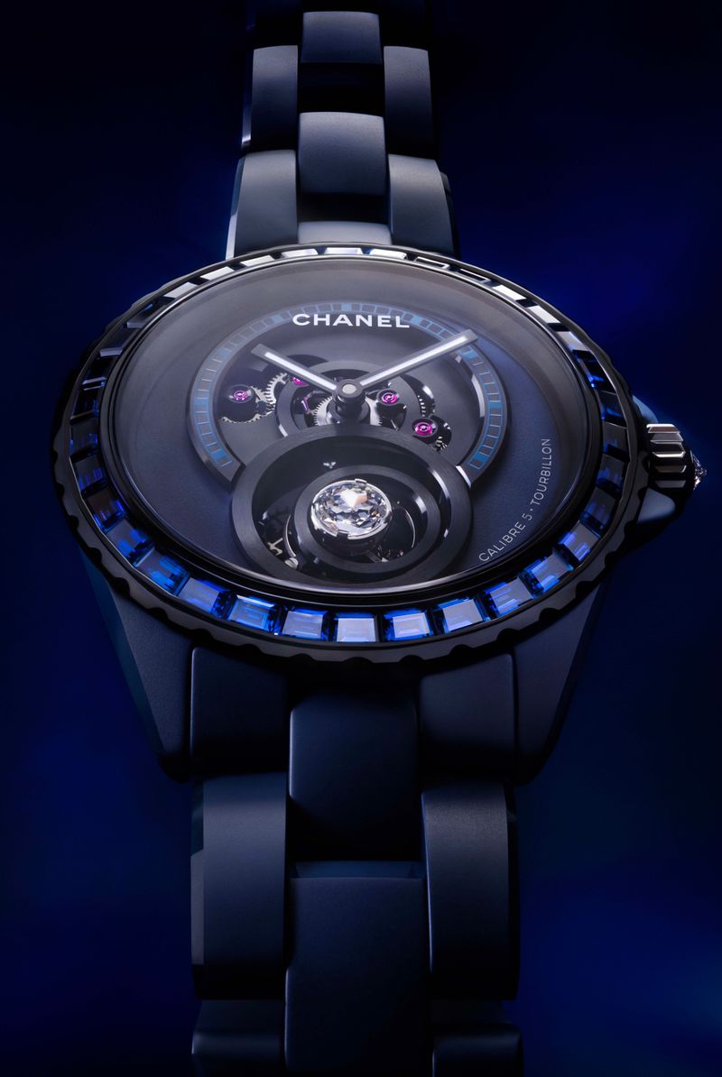 Elegant navy blue Chanel watch features a dark face, transparent inner mechanisms, sapphire embellishments, and a linked ceramic band.