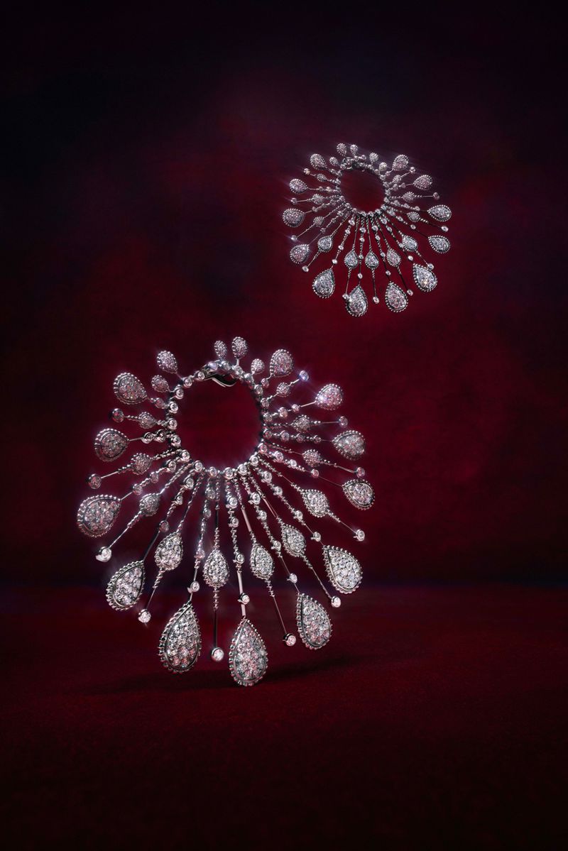 Two glittering diamond necklaces displayed against a rich red backdrop, catching the light with sparkling reflections and intricate detail.