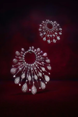 Two glittering diamond necklaces displayed against a rich red backdrop, catching the light with sparkling reflections and intricate detail.