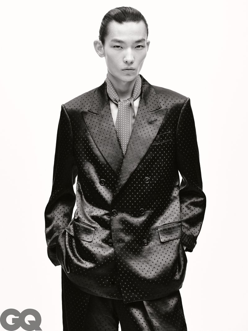 Portrait of a young adult Asian male fashion model in a dotted double-breasted suit and tie posing in a studio with white background.