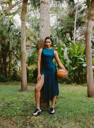 A'ja Wilson in a teal dress holding a basketball against a tree outdoors for American Vogue, photographed by Joshua Woods.