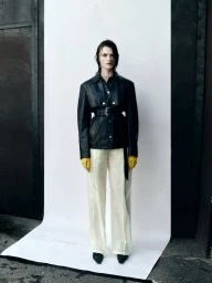 Model with wet hair wearing a black leather jacket and yellow gloves against a white seamless backdrop for Telva.