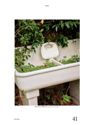 White woven leather handbag resting on a rustic concrete garden trough filled with green plants