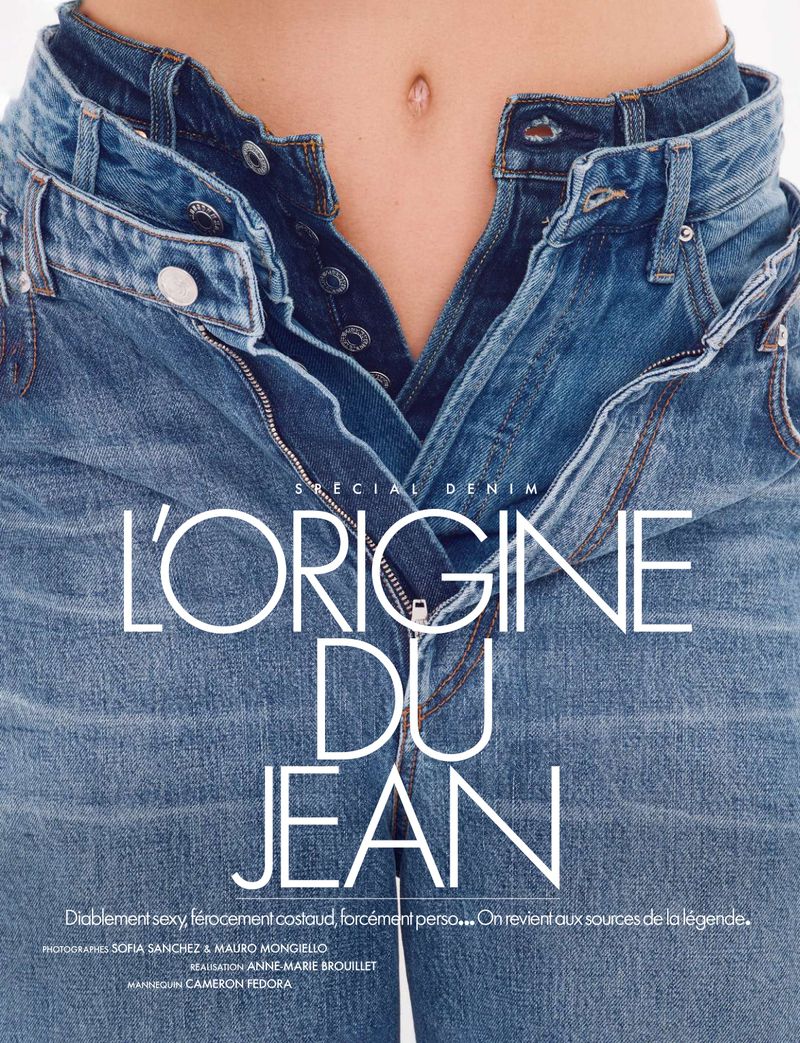 Close-up fashion shot of an adult with light skin wearing unbuttoned blue jeans in front of a white backdrop. Denim concept.