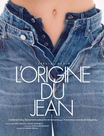 Close-up fashion shot of an adult with light skin wearing unbuttoned blue jeans in front of a white backdrop. Denim concept.
