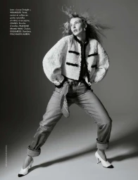 Black and white fashion editorial image featuring a model posing in a textured cropped jacket and cuffed jeans.