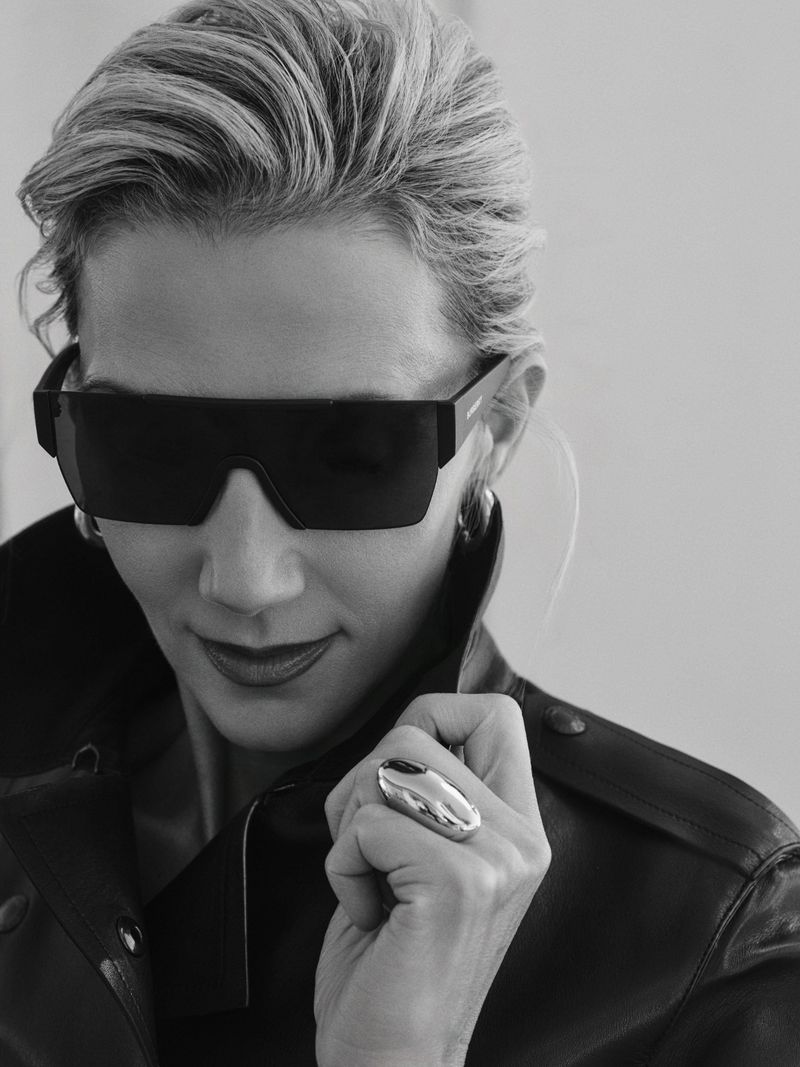 Portrait of a blonde woman wearing oversized dark sunglasses and a dark collared jacket, photographed by Jonny Marlow for Harper's Bazaar Greece.