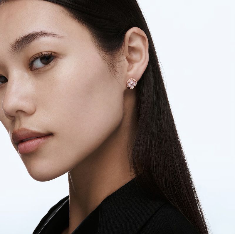 Close-up shot of a young Asian woman with flower earrings. The focus is on the woman's face and the jewelry detail against a clean backdrop.