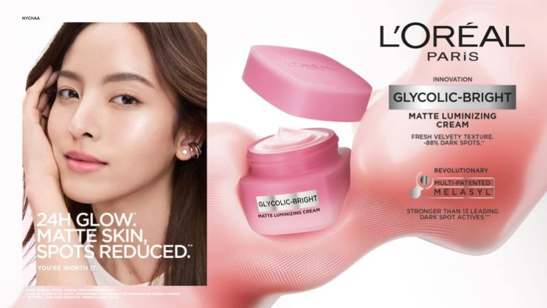 Cosmetics ad featuring an Asian woman promoting L'Oréal Glycolic-Bright Matte Luminizing Cream with bright, even-toned skin in a studio.