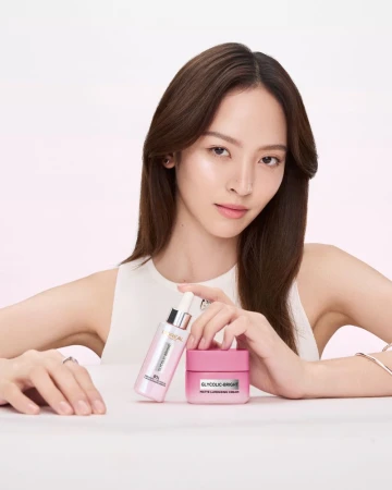 Cosmetic product promotion featuring a woman with long brown hair holding L'Oreal Glycolic-Bright serum and a jar of face cream.