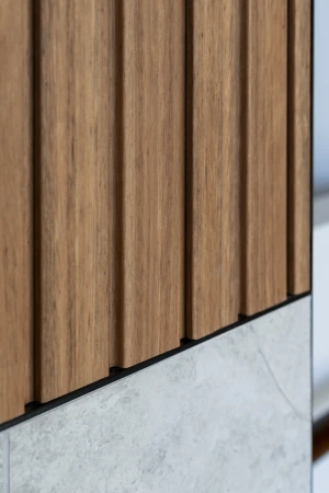 Close-up of a panel featuring vertical wood slats above a concrete slab wall, highlighting the texture and joinery.