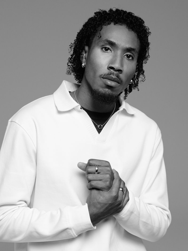 Black man wearing a white polo shirt and rings against a grey studio backdrop for the Pomellato For Women 2026 Campaign.