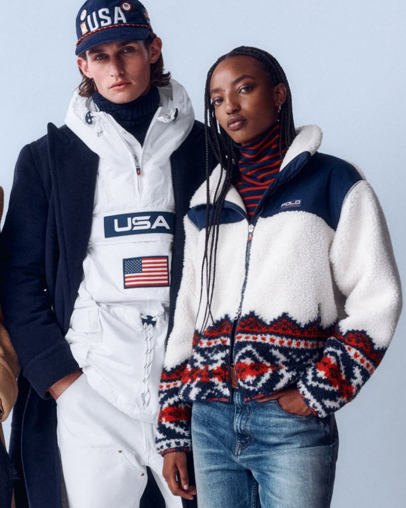 Two fashion models pose indoors in bright light wearing preppy winter clothing: jacket, hoodie, cap, turtleneck, coat and jeans.
