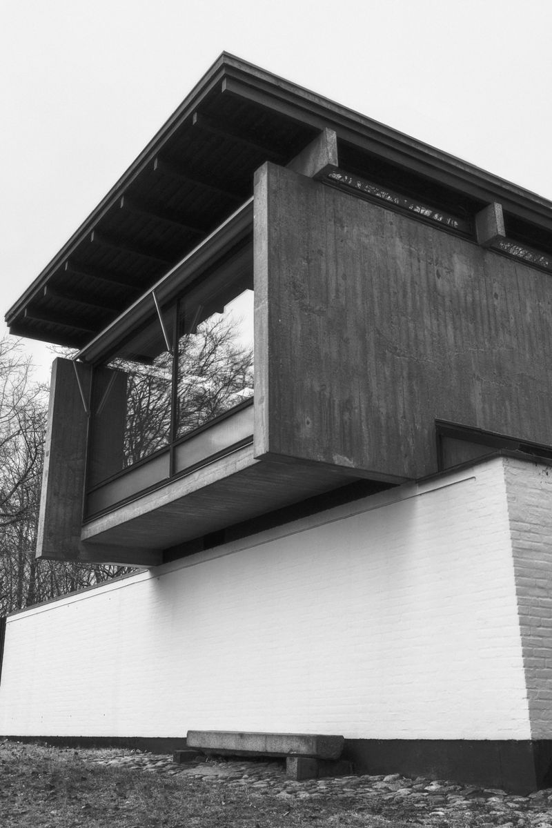 Exterior view of a modern architectural building featuring concrete and white brick, seen from a low angle against a light sky.