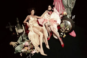 Two models posed on a dark set with candles, mirrors, and theatrical drapery for a fashion photography project by Willy Vanderperre.
