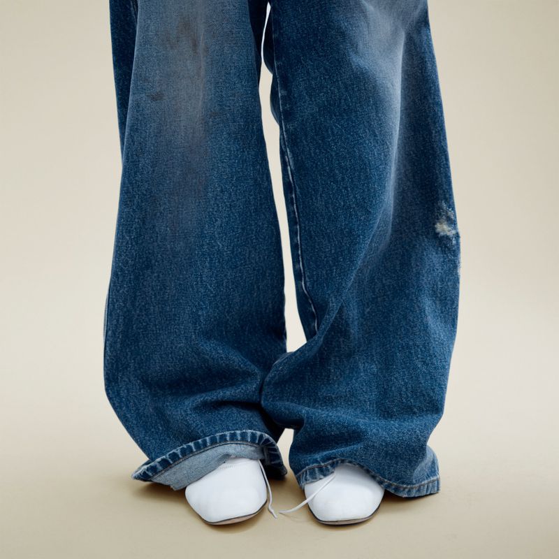 Denim jeans and white shoes. Lower half of a person wearing blue denim pants and white shoes. Fashionable denim.