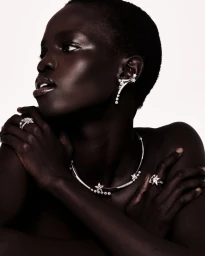 Close-up portrait of model Akolde Meen wearing fine diamond jewellery including earrings, a necklace, and rings.