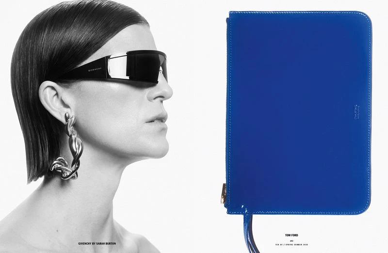 Fashion editorial shot: woman in sunglasses, twisted metal earrings, with a blue Tom Ford folio case on a white background.