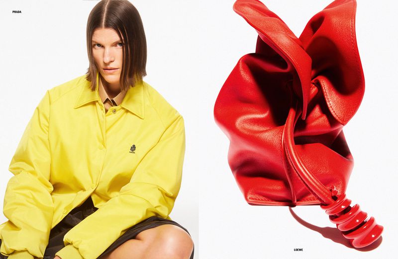 Editorial fashion shot of a female model in a yellow Prada jacket alongside a red Loewe handbag against a stark white background.