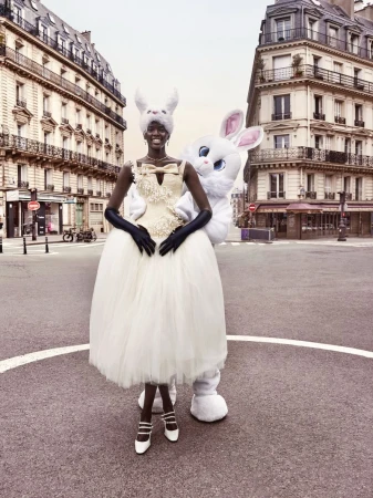 Fashion editorial shot in Paris featuring a Black woman wearing a ballgown and a furry rabbit headpiece next to a human-sized rabbit.