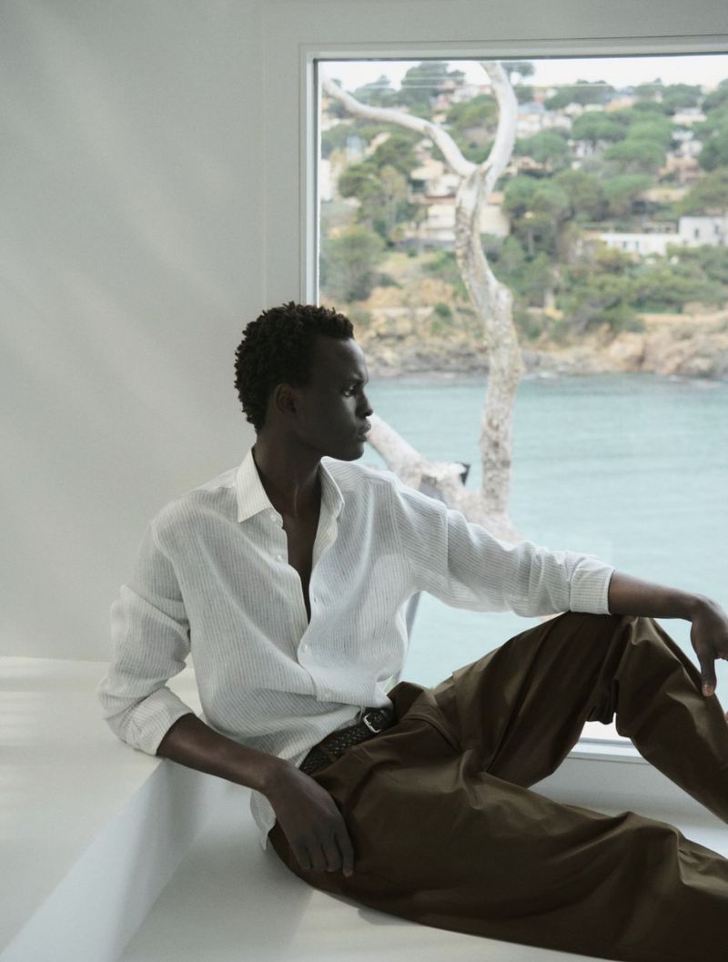 Black model seated near window wearing white shirt and brown trousers for Massimo Dutti SS26 collection