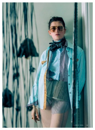 Fashion shot of a woman with sunglasses and a patterned outfit leaning against a wall with modern art for a high-end magazine.