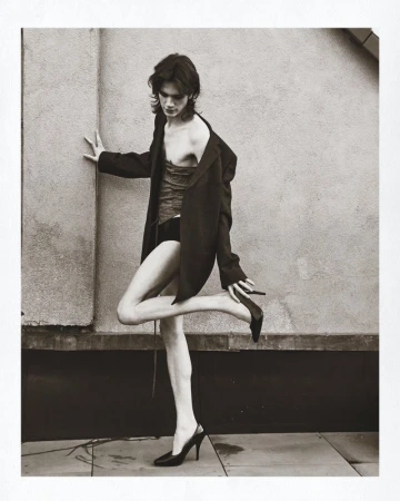 Model in oversized black blazer and heels posing against a textured wall for Numero Netherlands Blisters
