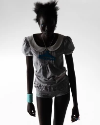 Model Aluel Keror wearing a grey top and shorts against a white seamless background for Lights Off for The Correct Distance