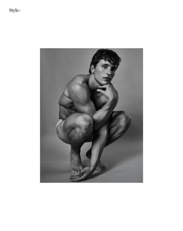 Monochrome portrait of male model Sergio Modrego crouching against a plain studio background for The Perfect Man Magazine.