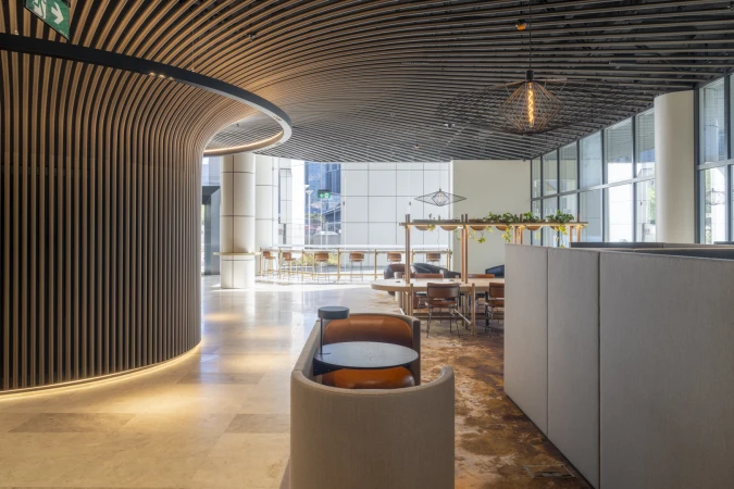Interior view of a modern office space with wooden ceiling slats, neutral furniture, and an open floor plan with natural light.