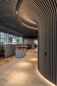 Curved slatted ceiling and matching curved wall paneling in a modern office interior by Daniel Cook for Keece Electrical