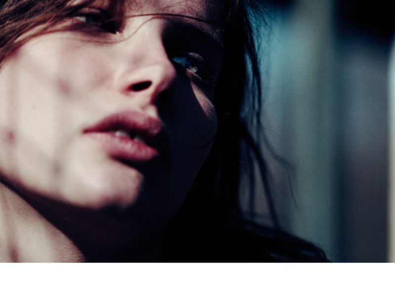 Close-up portrait of an adult woman with dark hair and fair skin with dramatic chiaroscuro lighting in an indoor environment.