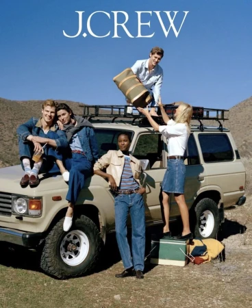 J.Crew fashion shot featuring five young adults posing on and around a beige SUV against a dry, hilly landscape under a clear blue sky.