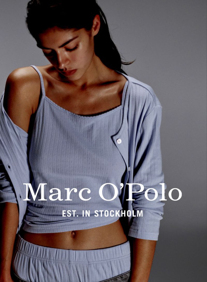 Close-up studio shot of a woman wearing a light-blue ribbed tank top and shorts, with a matching cardigan. Text overlay: Marc O'Polo.