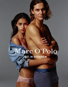 Man and woman posing together for Marc O'Polo, with the woman wearing a denim jacket and pink lingerie and the man wearing striped underwear.