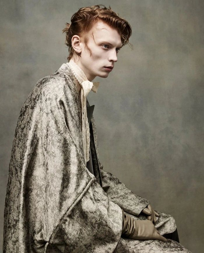 Model Owen Ruppersburg wearing a textured grey coat and lace cravat for ICON America SS26 by Sølve Sundsbø