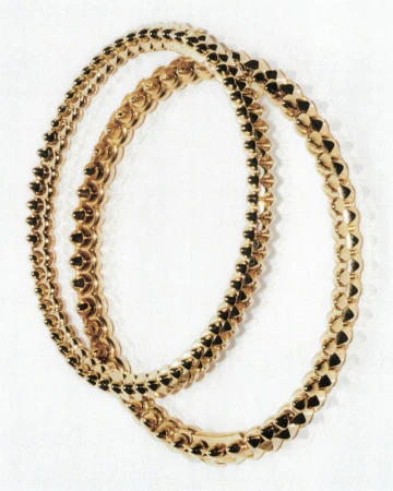 Two interlocking gold bracelets featuring a textured stud design resting against a clean white background