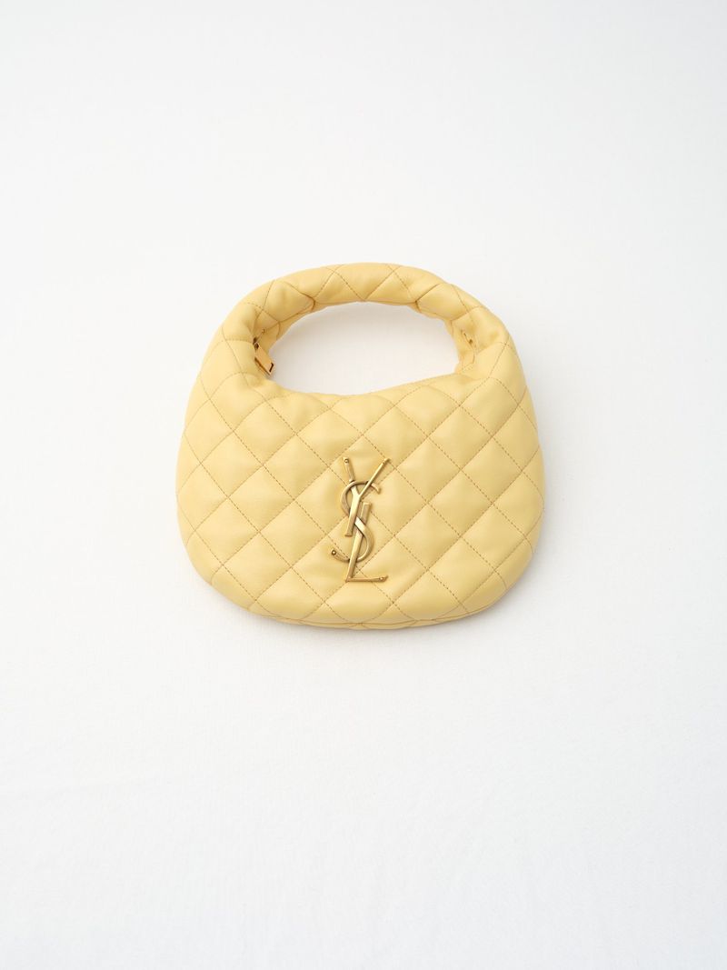 Light yellow quilted leather top-handle handbag with gold-tone YSL logo on a clean white background in a studio product shot.
